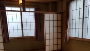 A tatami mat room with a low table, sliding doors, and a view through a shoji screen. - Hakuba Hotel Hana no Sato (Hakuba)