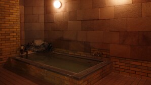 A spa area with a large bathtub, tiled walls, and two wall-mounted lights. - Hakuba Hotel Hana no Sato (Hakuba)