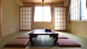 A traditional Japanese room with tatami flooring, a low table, and sliding shoji doors. - Hakuba Hotel Hana no Sato (Hakuba)