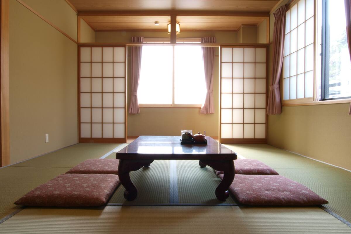 A traditional Japanese room with tatami flooring, a low table, and sliding shoji doors.