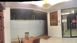 A dining area with a table and chairs, a wall with a sign reading "HIRAN RESIDENCE", and a glass door with a "KEY CARD ONLY" sign. - Hiran Residence (Patong)