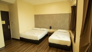 Ein Hotelzimmer mit zwei Betten, Holzboden, einem Wandtelefon und einer Tür.