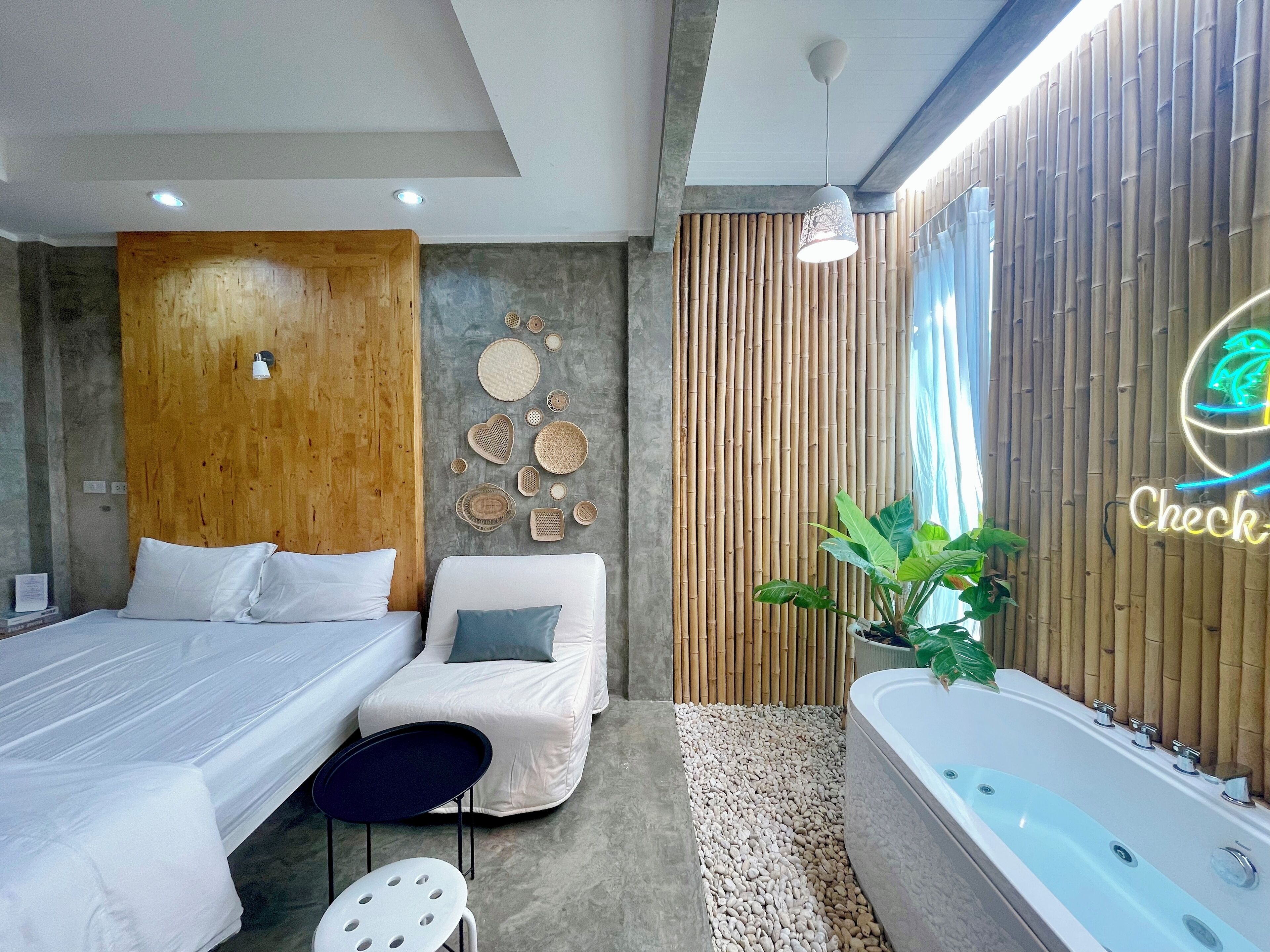 Una camera d'albergo moderna con un letto, un divano, un tavolino, una vasca da bagno e una parete decorata con oggetti e un neon.
