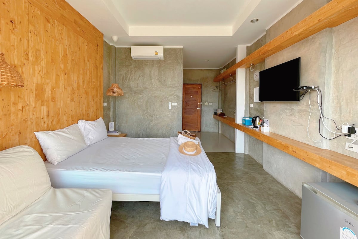 A modern bedroom with a bed, bedside table, and a television mounted on the wall.