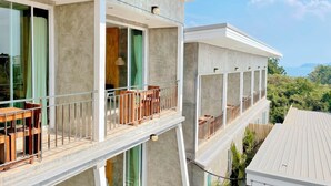 A multi-story building with balconies, large windows, and a view of greenery and mountains. - Check-in Resort Koh Larn (Koh Lan)