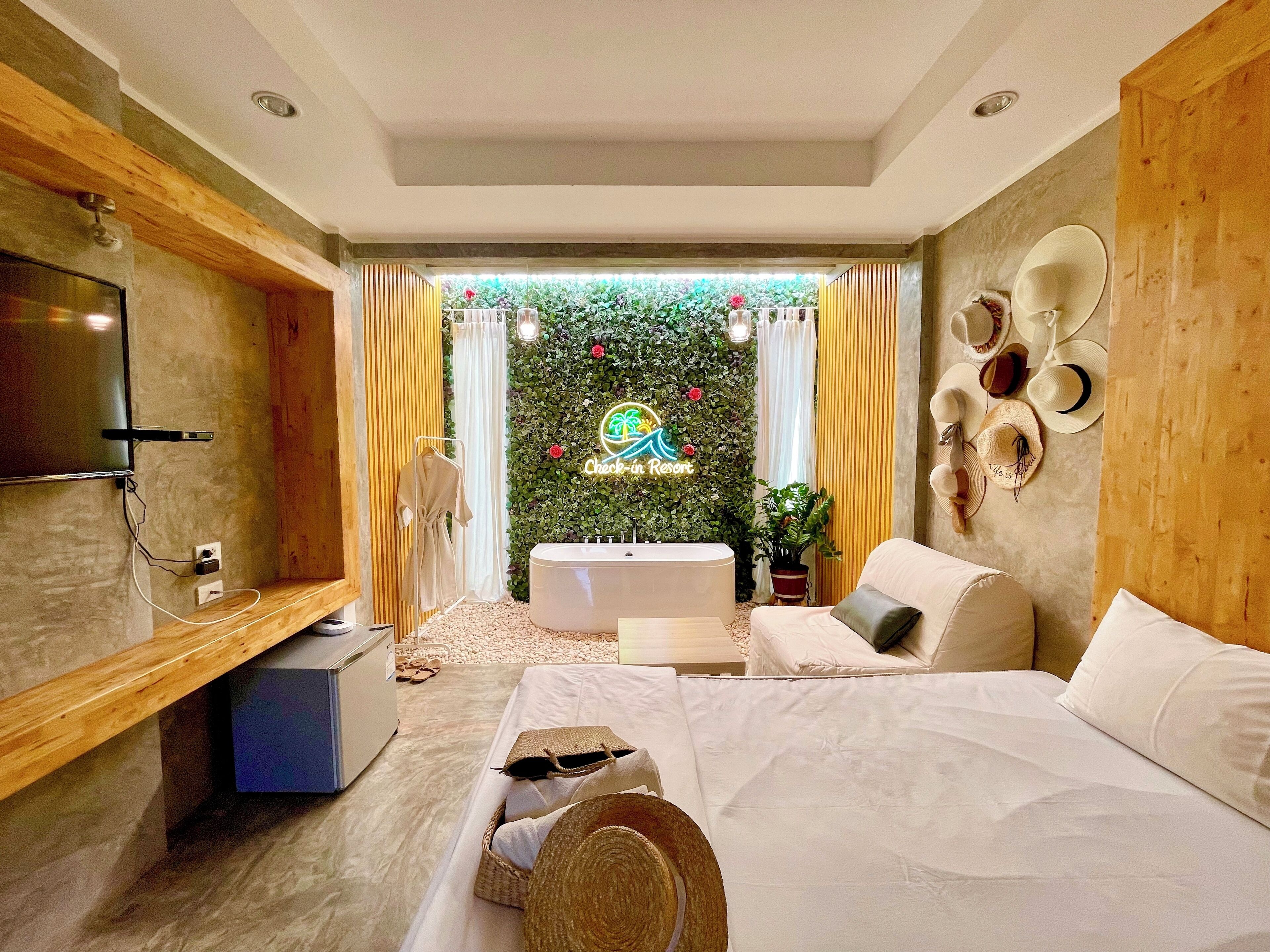 Habitación de hotel moderna con cama, televisor, tocador de madera y cartel de recepción.
