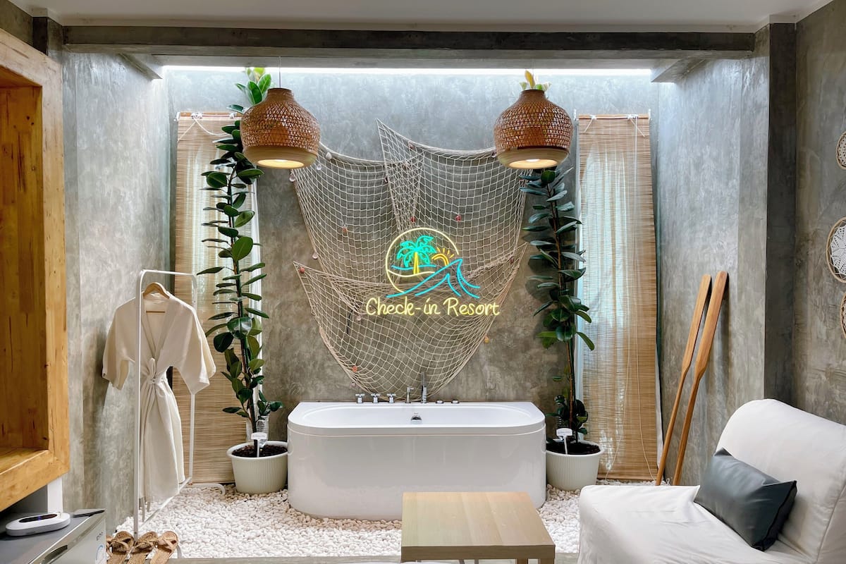 A modern bathroom with a freestanding bathtub, a white sofa, and a check-in sign.