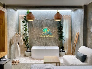 A modern bathroom with a freestanding bathtub, a white sofa, and a check-in sign. - Check-in Resort Koh Larn (Koh Lan)