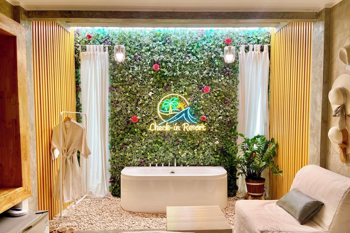 A spa room with a large bathtub, a sofa, and a wall decorated with greenery and flowers.
