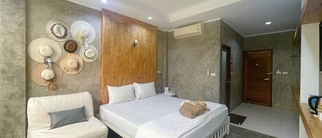 A hotel room with a bed, a seating area with a table, and a wall decorated with hats.