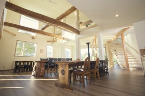 Un comedor amplio con vigas de madera, ventanas grandes y una escalera.