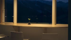 A room with a large window overlooking mountains at dusk. - Ryokan Mokuzin (Hakuba)