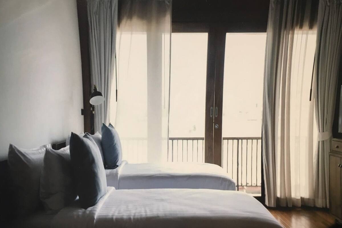 Quarto de hotel com duas camas, varanda e vista do céu.