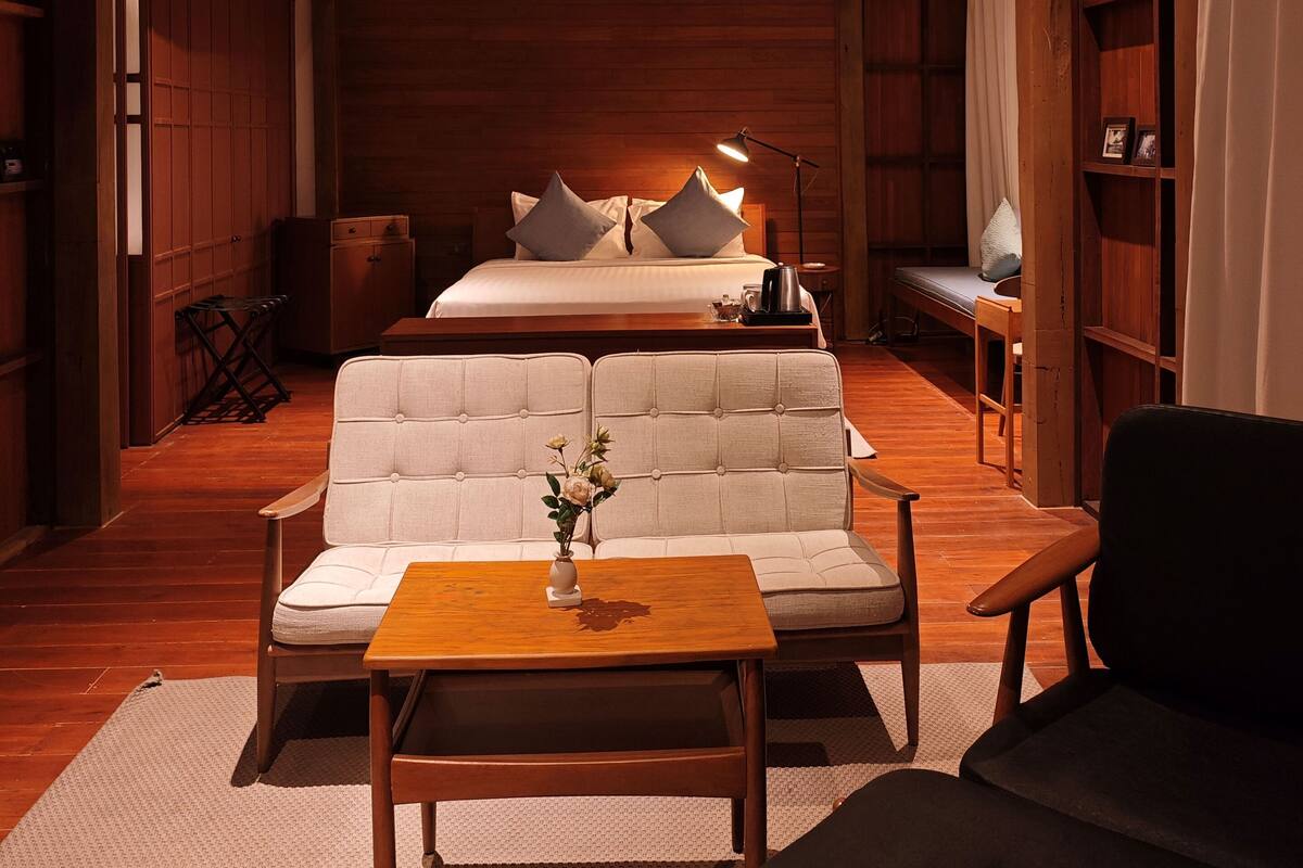 Quarto moderno com cama grande, sofá, mesa de centro e estante.