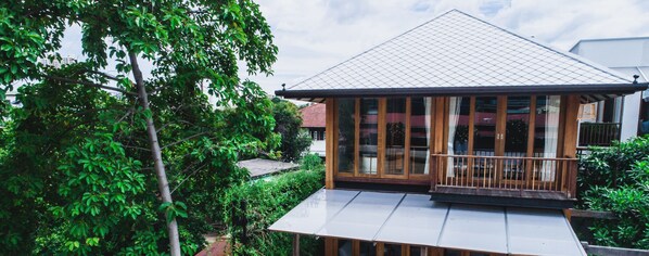 Una casa con techo de tejas, balcón de madera y ventanas amplias.