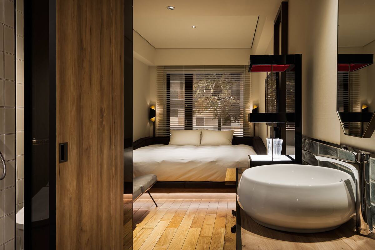 A modern bedroom with a large bed, a round bathtub, and a wooden floor.