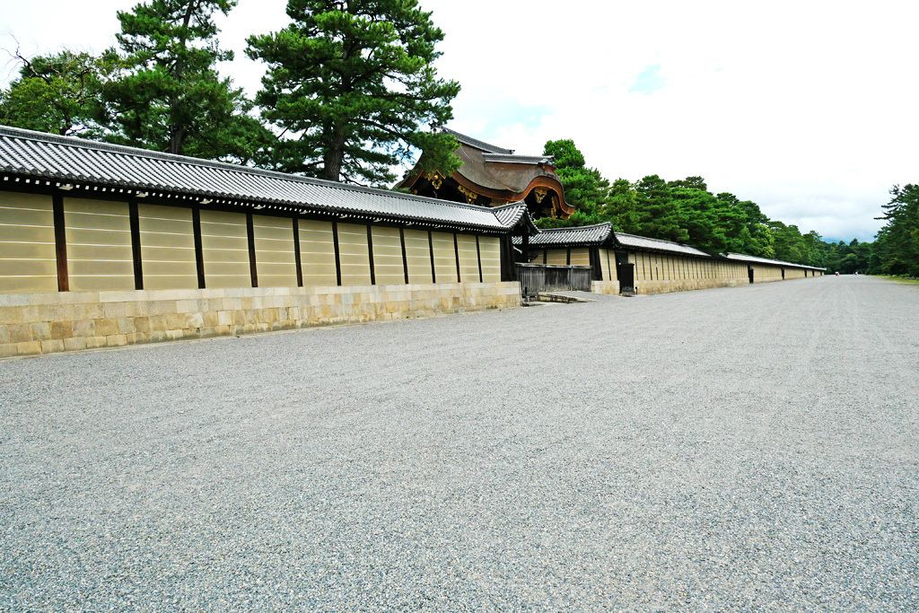 A traditional Japanese building with a long, straight pathway leading to a gate.