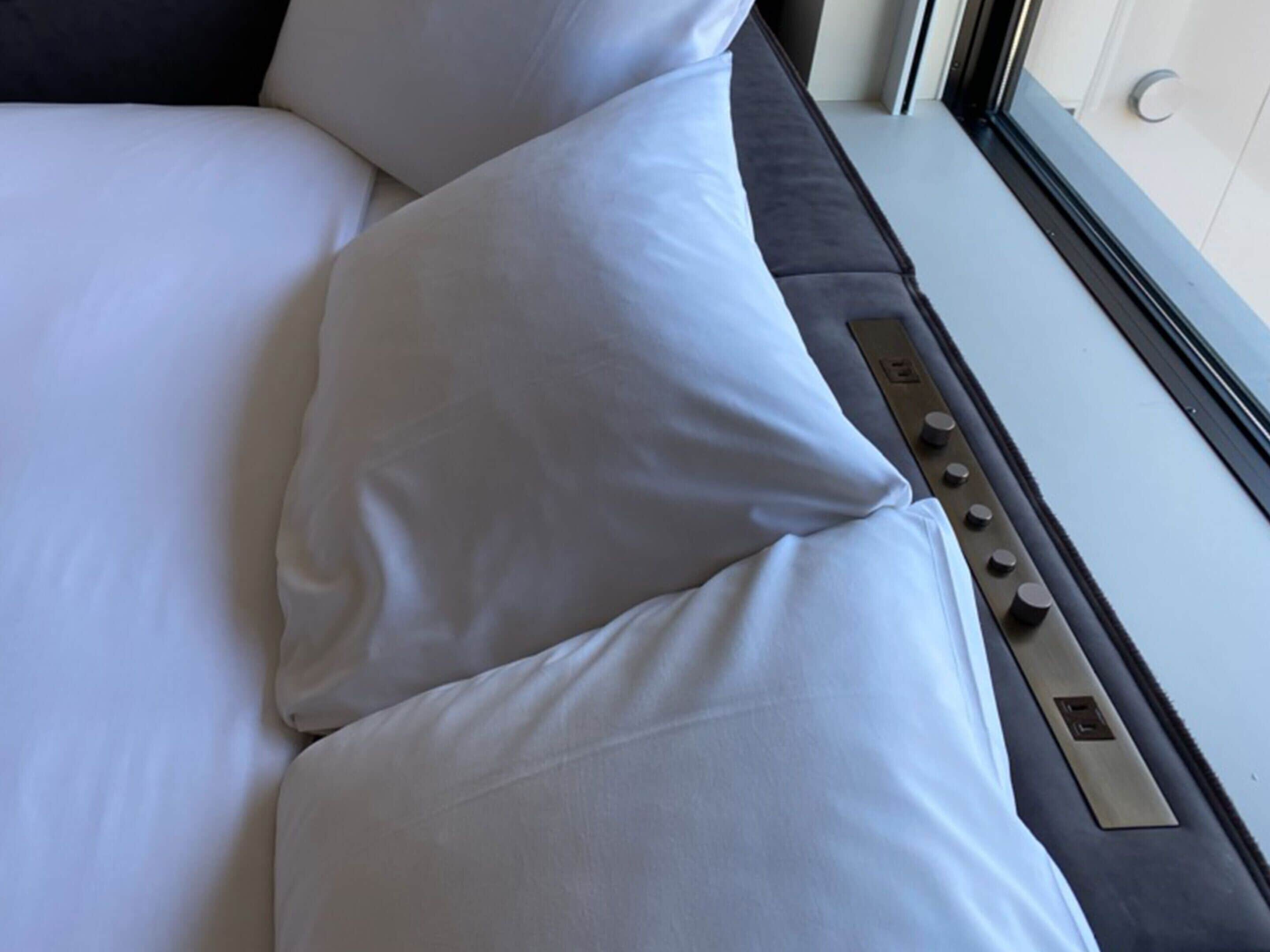 Ein Bett mit weißer Bettwäsche und einer Bedieneinheit an der Seite.