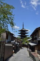 A traditional Japanese street with wooden buildings, a pagoda, and a clear blue sky.