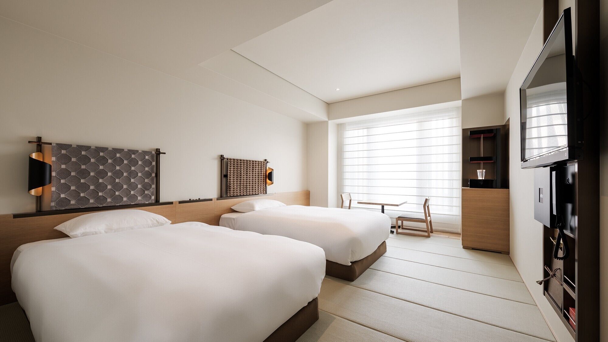 Una habitación de hotel con dos camas, televisor, escritorio y ventana con persianas.