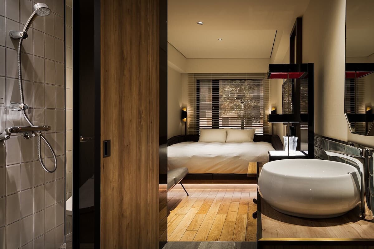 A modern bathroom with a shower, a large sink, and a bed with a view of the outdoors.