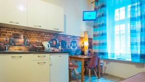 Una cucina moderna con mobili bianchi, zoccolo in mattoni e zona pranzo con tavolo e sedie.