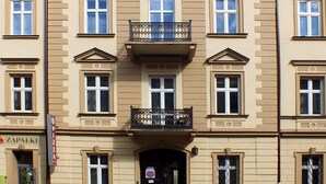 Un edificio a più piani con una facciata simmetrica, caratterizzata da finestre regolarmente disposte e un balcone centrale con ringhiere elaborate.