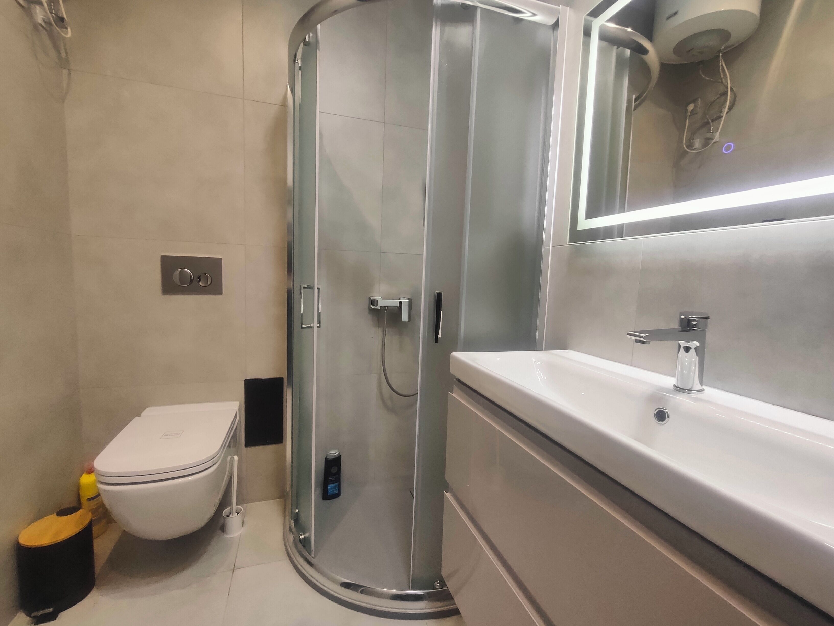Een moderne badkamer met een douchecabine van glas, een wit toilet en een wastafel met spiegel.