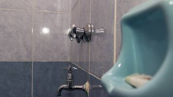 A bathroom with a urinal, a faucet, and tiled walls.