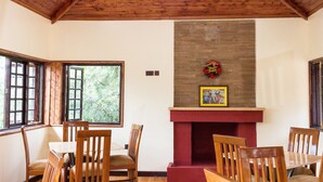 A dining area with wooden furniture and a fireplace. - Kuniville Guest House (Nyeri)