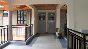 A hallway with a wooden ceiling, stone walls, and a potted plant. - Kuniville Guest House (Nyeri)
