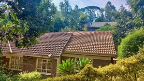A house with a tiled roof, surrounded by lush greenery and trees. - Kuniville Guest House (Nyeri)