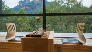 Un bureau en bois donnant sur un paysage montagneux grâce à de grandes fenêtres.