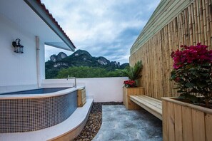 A spa area with a hot tub, wooden benches, and a view of mountains.
