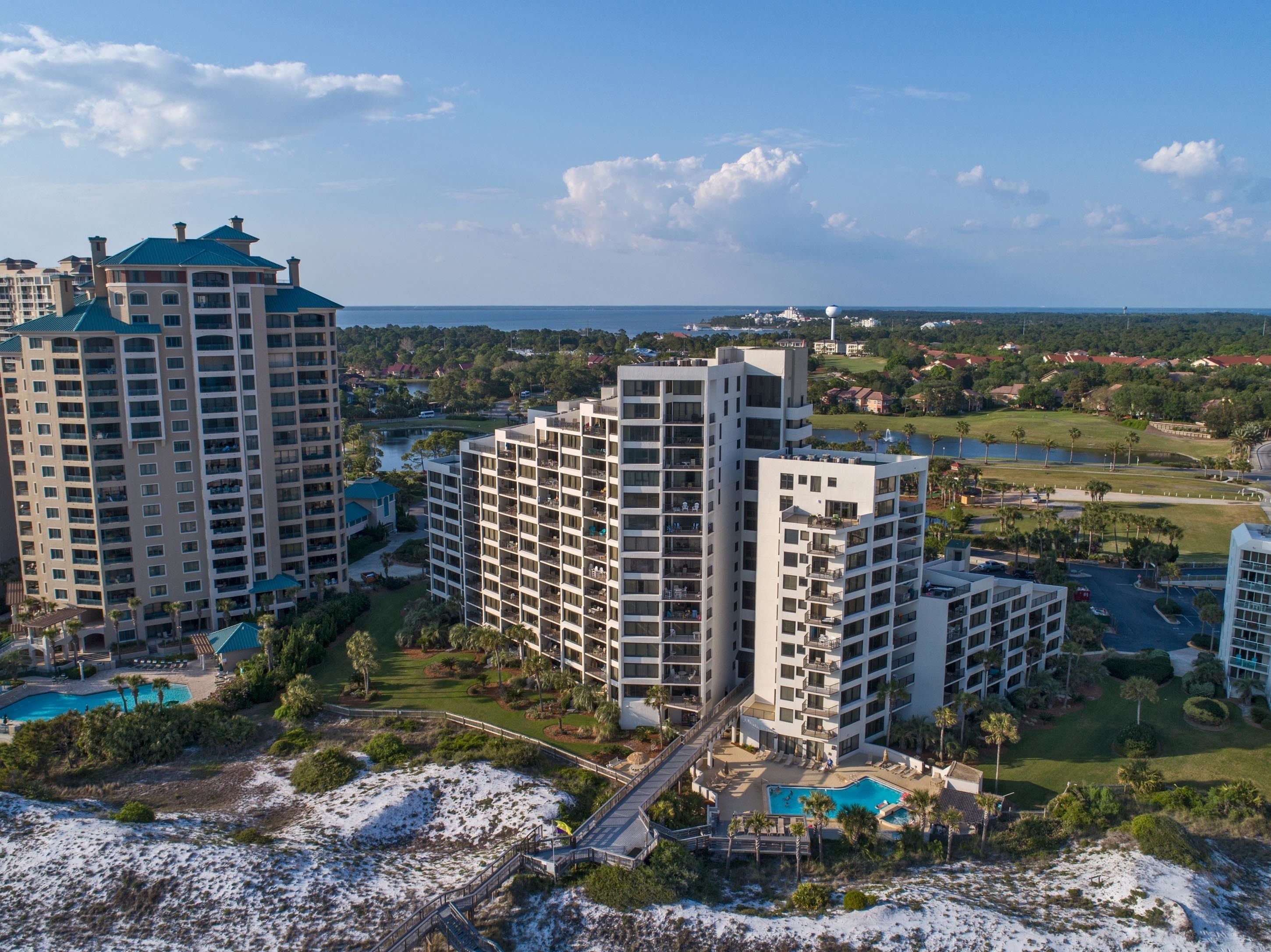A high-rise hotel with multiple balconies, a swimming pool, and a view of the surrounding landscape.