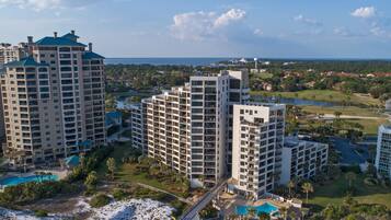 A high-rise hotel with multiple balconies, a swimming pool, and a view of the surrounding landscape.