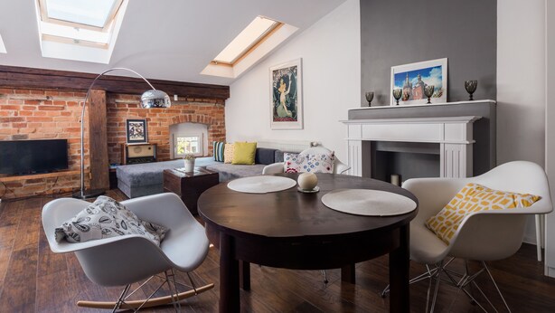 A modern living room with a fireplace, a round dining table, and a cozy seating area. - Apartamenty Amber (Kraków)
