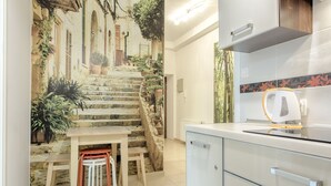 A kitchen with a stone staircase, a table with chairs, and a modern coffee maker. - Apartamenty Amber (Kraków)