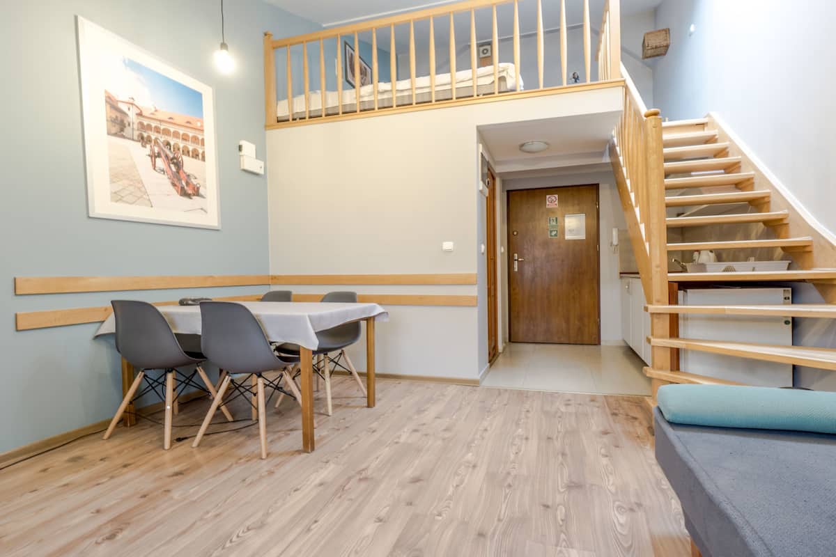 Un comedor con una mesa y sillas, una escalera y una puerta que da a otra habitación.