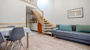 A modern living room with a staircase, a dining area, and a kitchen. - Apartamenty Amber (Kraków)