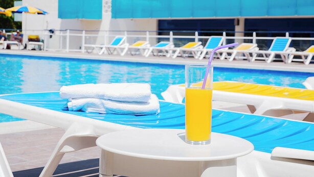 A poolside area with lounge chairs, a table with a drink, and towels. - Ona Palamós (Palamós)