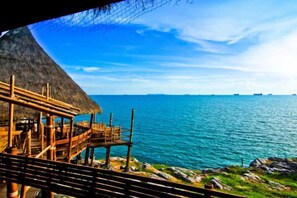 A wooden structure with a thatched roof overlooking a calm sea.