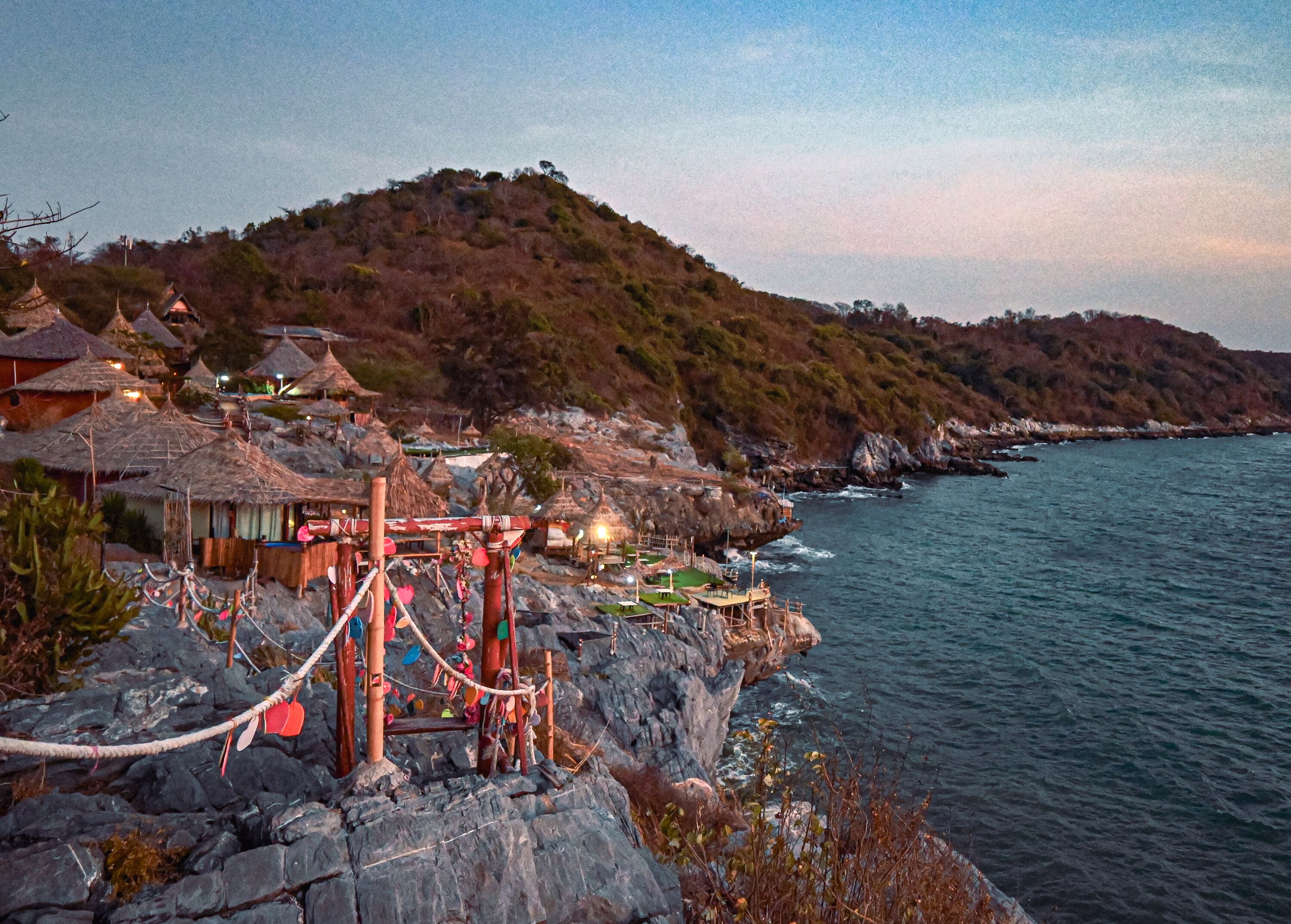 Un pueblo costero con casas de techo de paja tradicionales, una costa rocosa y una vista despejada del mar.