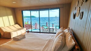 Una habitación con cama, sofá y un ventanal con vistas al mar y un muelle.