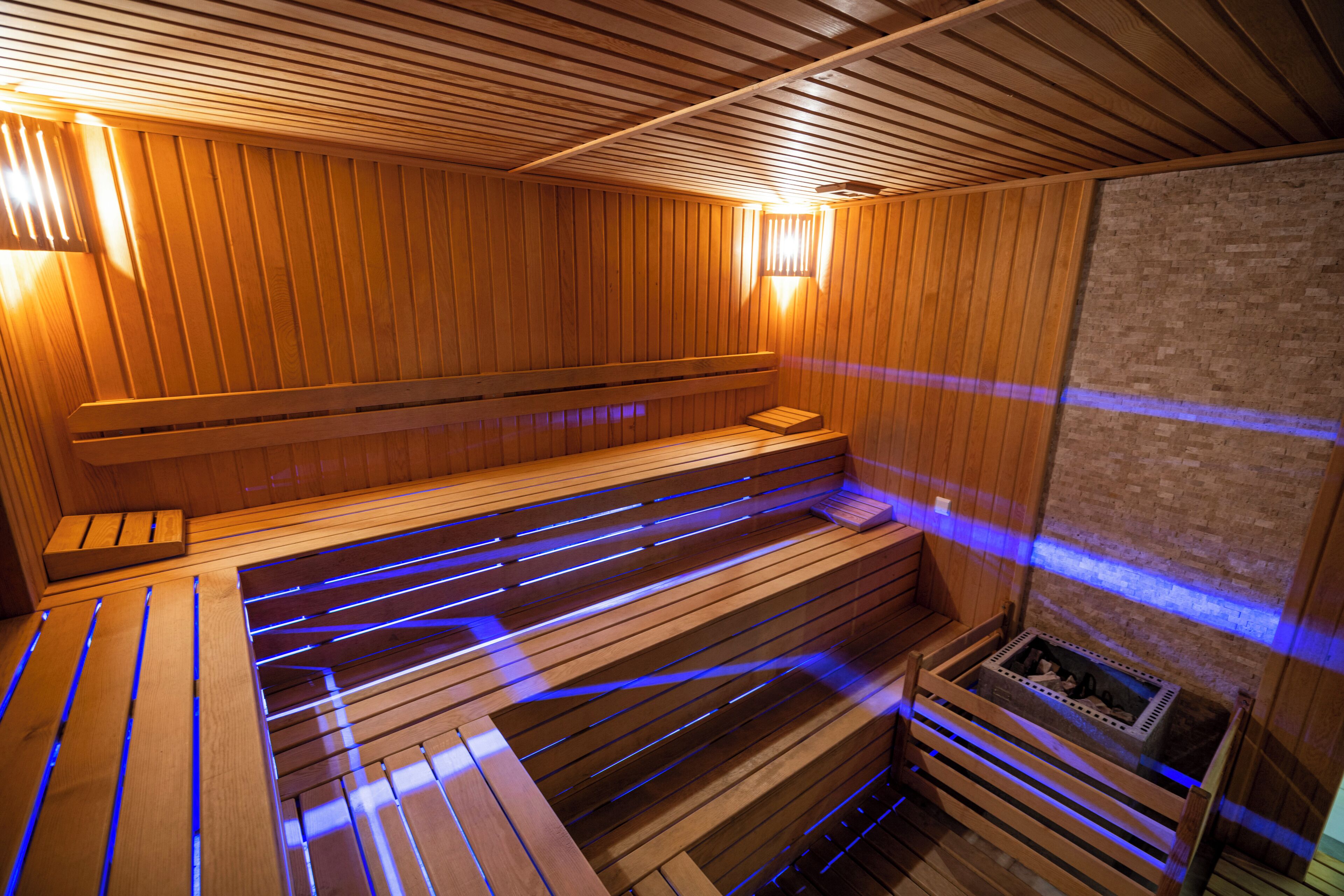 A sauna with wooden benches and a brick wall.