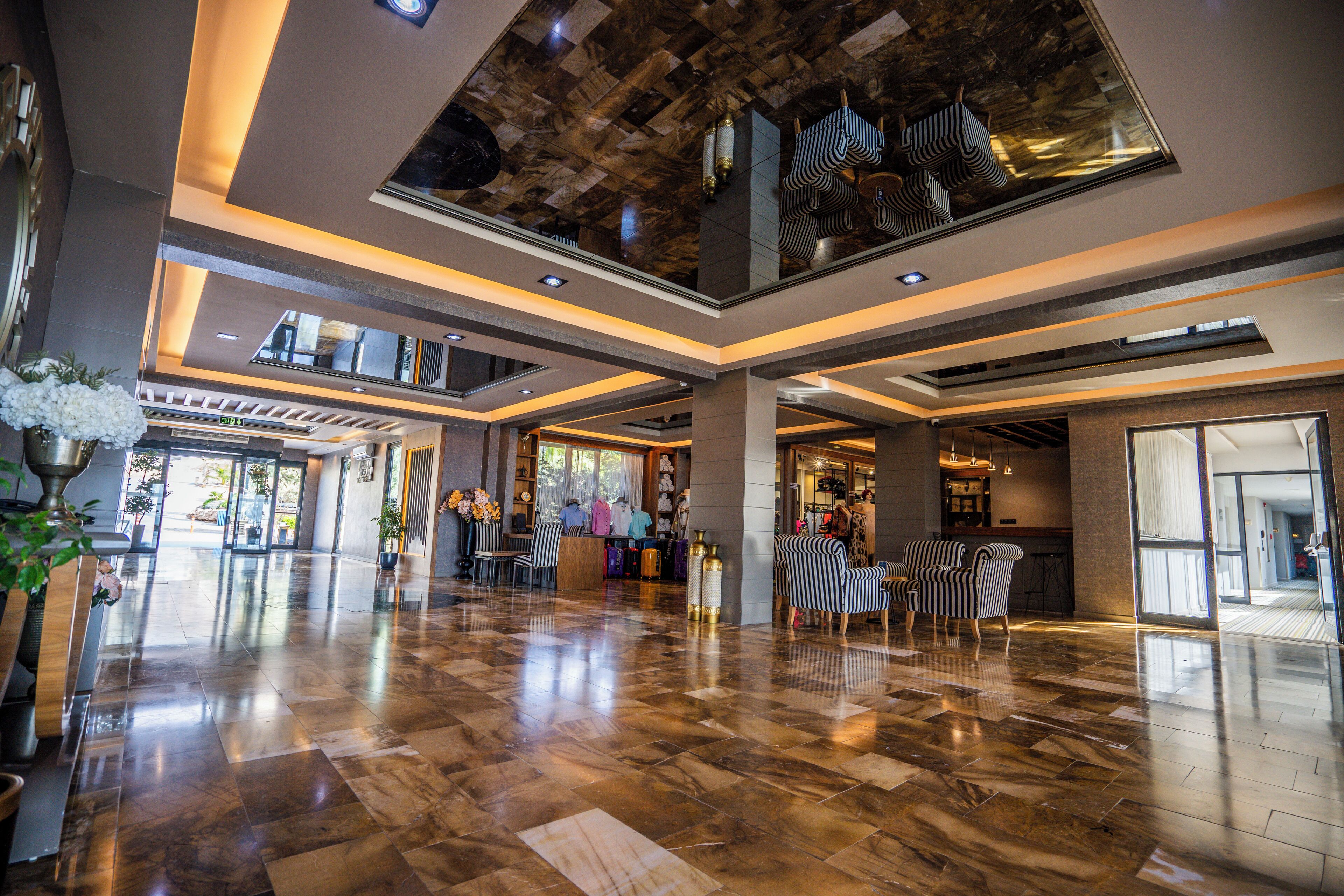 A spacious lobby with a polished marble floor, a reception desk, and striped chairs.