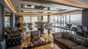 A spacious lobby with a high ceiling, large windows, and a variety of seating options including sofas and armchairs. - Hierapark Thermal & Spa Hotel (Denizli)