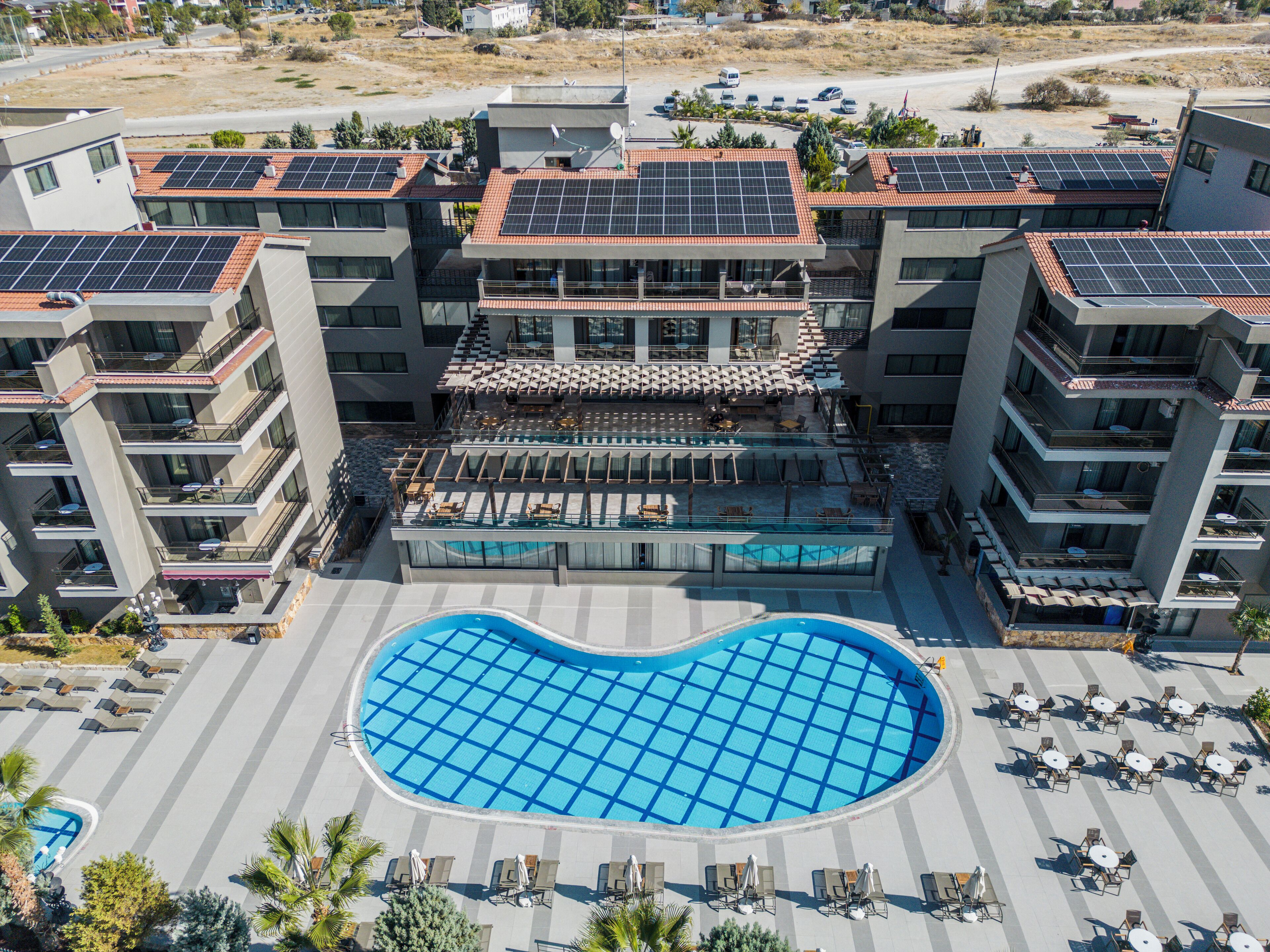 Un hôtel moderne doté d’une piscine sur le toit, de nombreux balcons et de panneaux solaires.