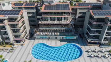 Un hôtel moderne doté d’une piscine sur le toit, de nombreux balcons et de panneaux solaires.