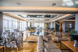 Un lobby amplio con una mesa redonda central, varias zonas de estar y un techo alto con tragaluces.